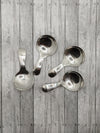 Four silver serving spoons with a solid pattern, displayed against a wooden background.